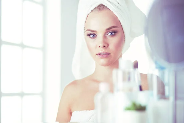 Fiatal nő fürdőköpenyben nézi fürdőszoba tükör — Stock Fotó