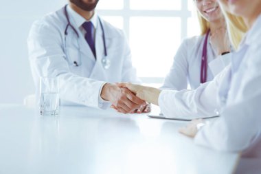 Doktor ofiste erkek bir hastayla el sıkışıyor.