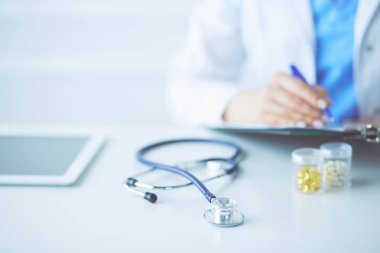 Kadınların elleri bir kağıt parçasına yazı yazıp masasında kalem bırakırlar.