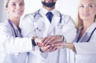 Doktorlar ve hemşireler tıbbi bir ekipte el ele tutuşuyorlar.