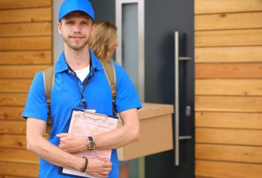 Mavi üniformalı gülümseyen kurye servis konseptine paket kutusu teslim eden teslimatçı. Mavi üniformalı gülümseyen teslimatçı.