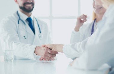 Doktor ofiste erkek bir hastayla el sıkışıyor.