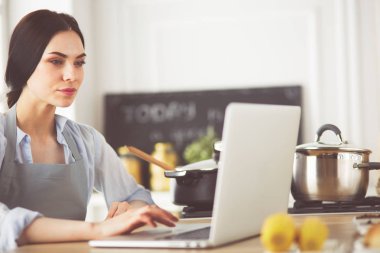 mutlu bir kadın mutfakta o onu laptop haber okuma