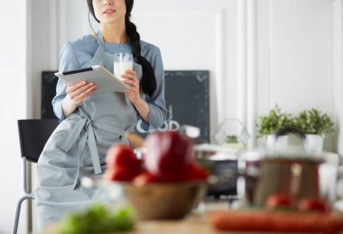 Tablette tarifi takip eden bir kadın evde yemek pişiriyor.