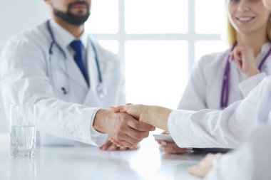 Doktor ofiste erkek bir hastayla el sıkışıyor.