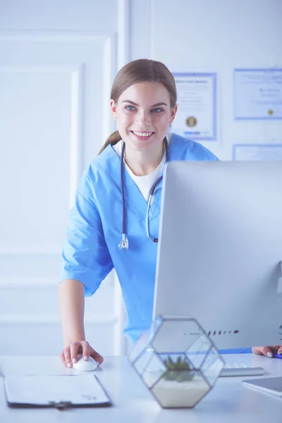 Mladá žena lékař v práci, zatímco ukazuje na počítač v nemocniční kanceláři. — Stock fotografie
