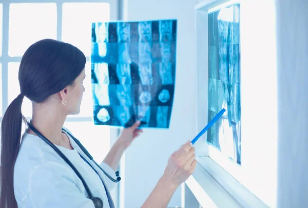 Young smiling female doctor with stethoscope pointing at X-ray at doctors office — Stock Photo, Image