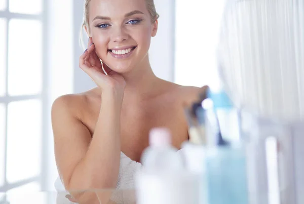 Una foto de una mujer joven aplicando polvo facial en el baño — Foto de Stock