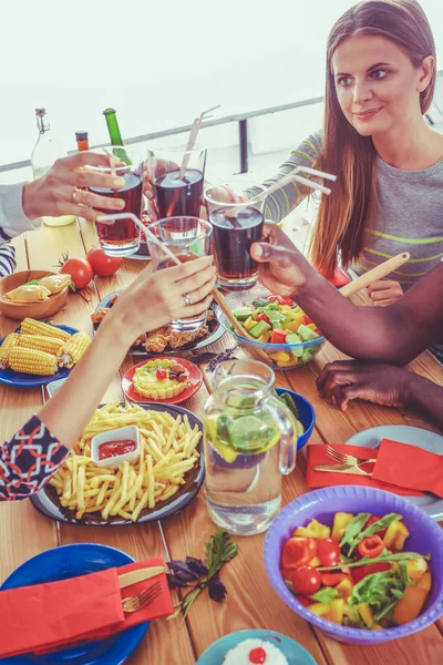 Pandangan utama dari sekelompok orang makan malam bersama saat duduk di meja kayu. Makanan di atas meja. Orang makan makanan cepat saji. — Stok Foto