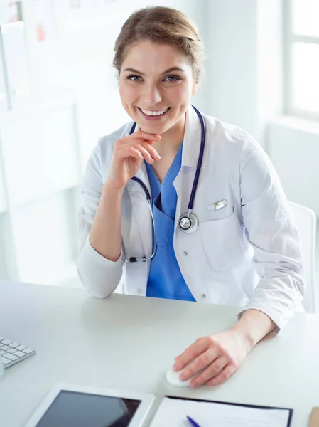 Young female doctor sitting at a desk and working on the computer at the hospital office. Health care, insurance and help concept. Physician ready to examine patient — Stock Photo, Image