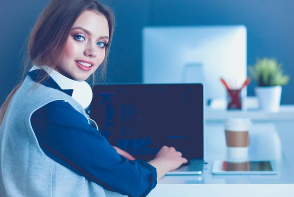 Молодая уверенная в себе деловая женщина, работающая за столом офиса и печатающая с ноутбуком — стоковое фото