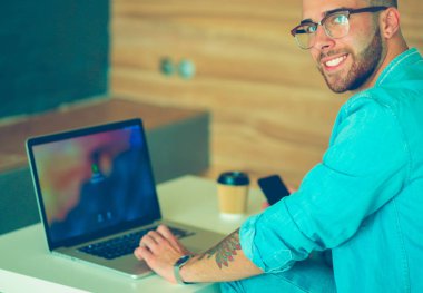 Genç bir telefonu kullanarak ve bir dizüstü bilgisayarda çalışan adam. Öğrenci manifatura telefon.