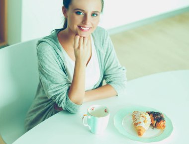 Mutfak masasında tatlı kruvasan ile çay içme kadın.