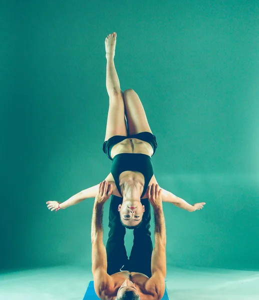 Casal jovem praticando acro ioga no tapete em estúdio juntos. Acroyoga. Um par de ioga. Parceiro ioga . — Fotografia de Stock