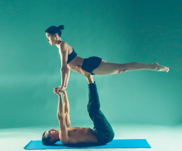 Cuplu tânăr care practică acro yoga pe mat în studio împreună. Acroyoga. Câteva yoga. Partener yoga . — Fotografie, imagine de stoc
