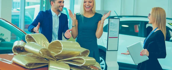 Een man maakt een geschenk - een auto aan zijn vrouw. Ze is hier verbaasd over. Ze zijn hier erg blij mee. — Stockfoto