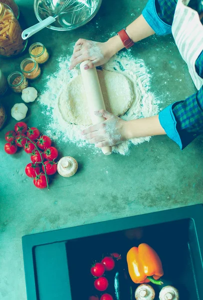 Güzel bir kadın mutfakta pasta pişiriyor. Masanın yanında duruyor..