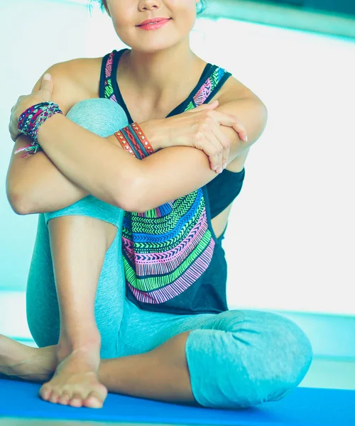 Retrato de una mujer sonriente de yoga sentada en la esterilla de yoga después del entrenamiento en el estudio de yoga. Yoga. Mujer. . — Foto de Stock