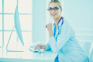 Hastanede masasında oturan genç bir kadın doktorun portresi.