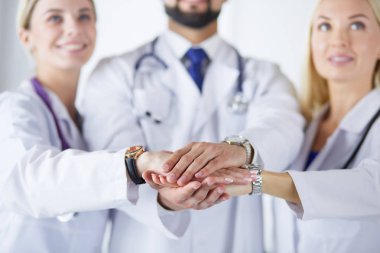Doktorlar ve hemşireler tıbbi bir ekipte el ele tutuşuyorlar.