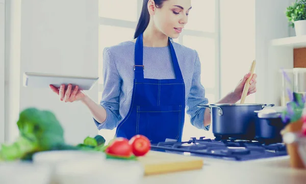 Jonge vrouw met behulp van een tablet computer om te koken in haar keuken — Stockfoto