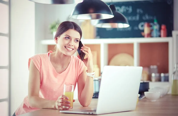 Young woman in kitchen with laptop computer looking recipes, smiling. Food blogger concept — Stock Photo, Image