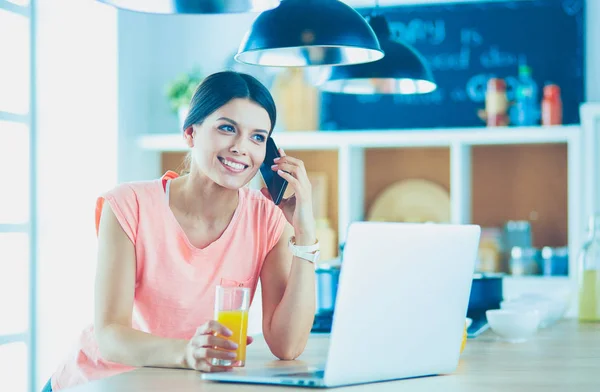 Mujer joven en la cocina con computadora portátil buscando recetas, sonriendo. Concepto de bloguero de alimentos —  Fotos de Stock