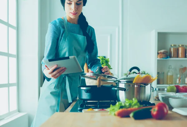 Junge Frau kocht mit Tablet-Computer in ihrer Küche — Stockfoto