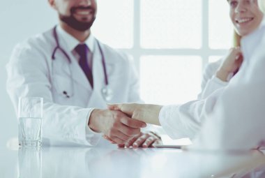 Doktor ofiste erkek bir hastayla el sıkışıyor.