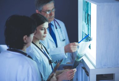 Bir grup doktor bir klinikte röntgenleri inceliyor, teşhis koymayı düşünüyorlar.