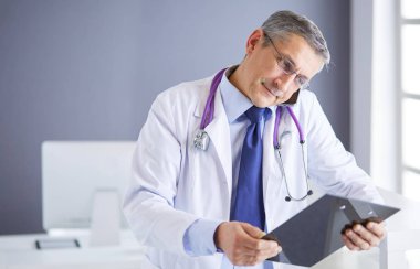 Erkek doktor hastanedeki panoya notlar yazıyor.