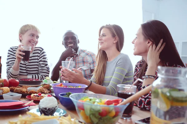 Ahşap masada otururken birlikte yemek yiyen bir grup insanın üst düzey görüntüsü. Masada yemek var. İnsanlar fast food yiyor..