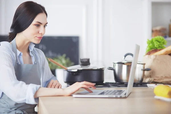 Jeune femme utilisant une tablette informatique pour cuisiner dans sa cuisine. — Photo