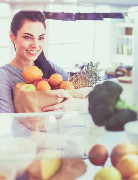 Smiling woman taking a fresh fruit out of the fridge, healthy food concept — Stock Photo, Image