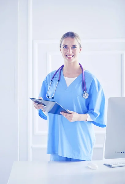 Médico sonriente con una carpeta en uniforme de pie — Foto de Stock