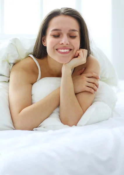 Pretty woman lying down on her bed at home.