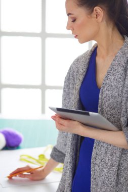 Güzel genç bir kadın dijital tablet üzerinde çalışıyor ve çalışırken gülümsüyor.