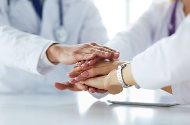 Doktorlar el ele tutuşup yakın çekim yapıyor.