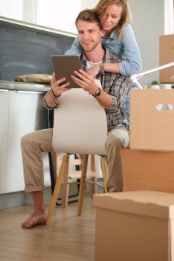 Genç bir çift yeni ev içinde hareket. Oturma ve açma sonra rahatlatıcı. Bir şey üstünde laptop arıyorum. Genç Çift