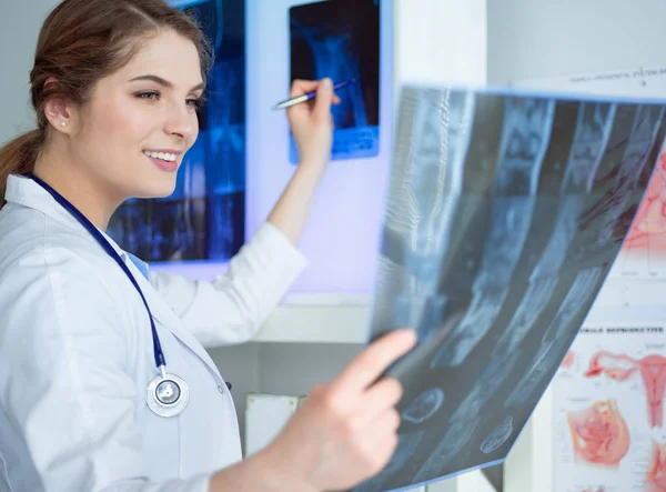 Jonge professionele vrouwelijke arts die patiënten röntgenfoto onderzoekt — Stockfoto
