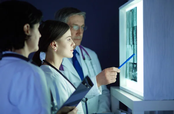 Bir grup doktor bir klinikte röntgenleri inceliyor, teşhis koymayı düşünüyorlar. — Stok fotoğraf