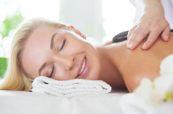 Mujer joven en el salón de spa, recibiendo piedras masaje — Foto de Stock