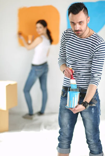 Retrato de feliz casal sorrindo jovem pintura parede interior da nova casa. jovem casal — Fotografia de Stock