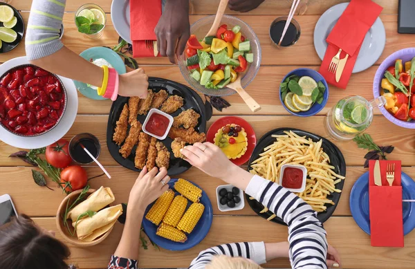 Vista superior do grupo de pessoas que jantam juntas enquanto estão sentadas à mesa de madeira. Comida na mesa. As pessoas comem fast food. — Fotografia de Stock