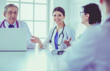 Ciddi bir tıbbi ekip hastaları parlak bir ofiste tartışıyor.