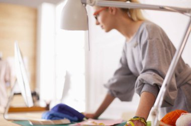 Moda tasarımcısı kadın stüdyoda tasarımları üzerinde çalışıyor.