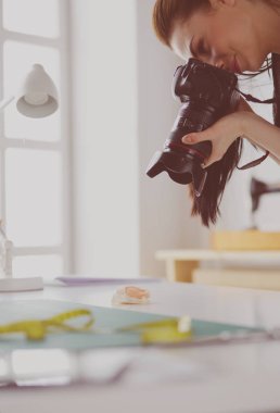 İşyerinin yanında duran ve dijital fotoğraf makinesinde fotoğraflayan genç kadın tasarımcı