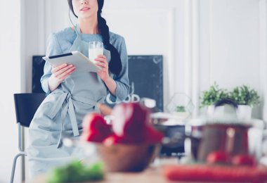 Tablette tarifi takip eden bir kadın evde yemek pişiriyor.