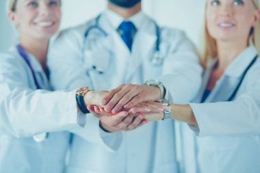 Doktorlar ve hemşireler tıbbi bir ekipte el ele tutuşuyorlar.