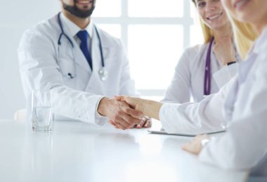 Doktor ofiste erkek bir hastayla el sıkışıyor.